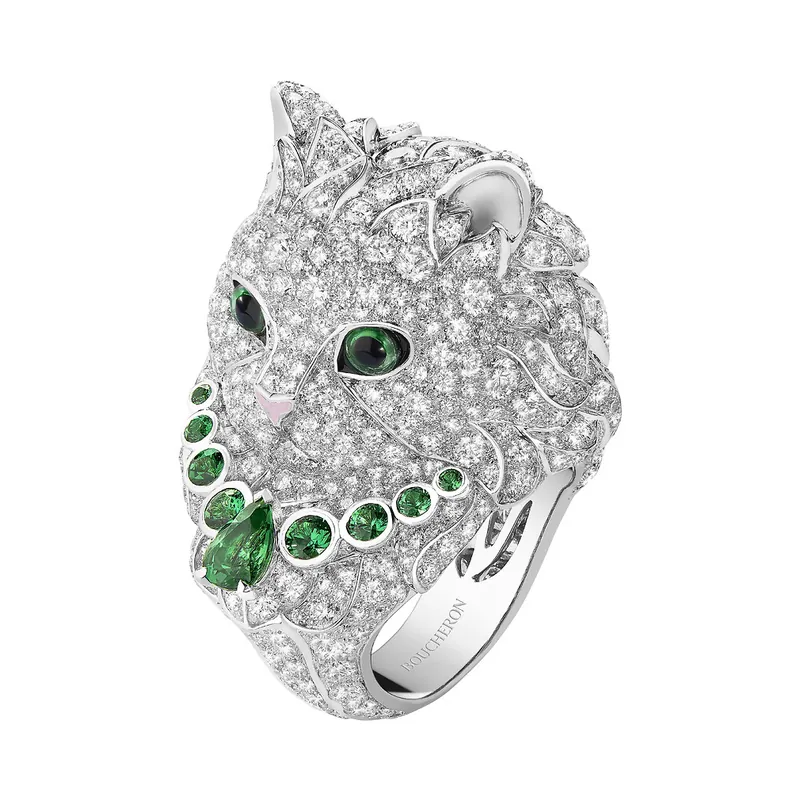 Wladimir the Cat ring in white gold: a cat's head paved with white diamonds, green stone eyes and a green gem necklace, on a white ground.