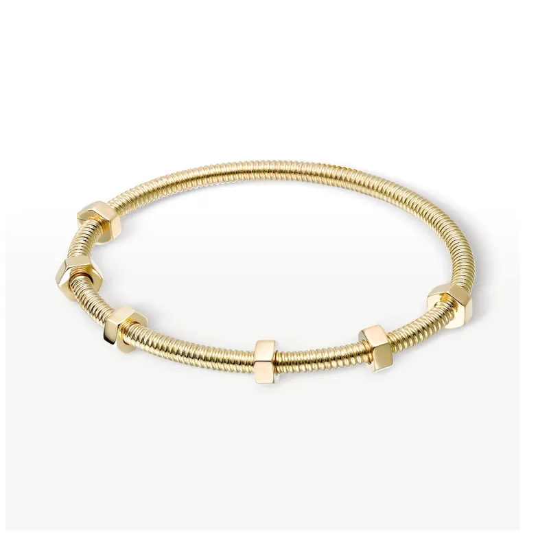 Écrou de Cartier bracelet in yellow gold: a thin threaded bangle carrying small hexagonal nuts, on a pale grey ground.