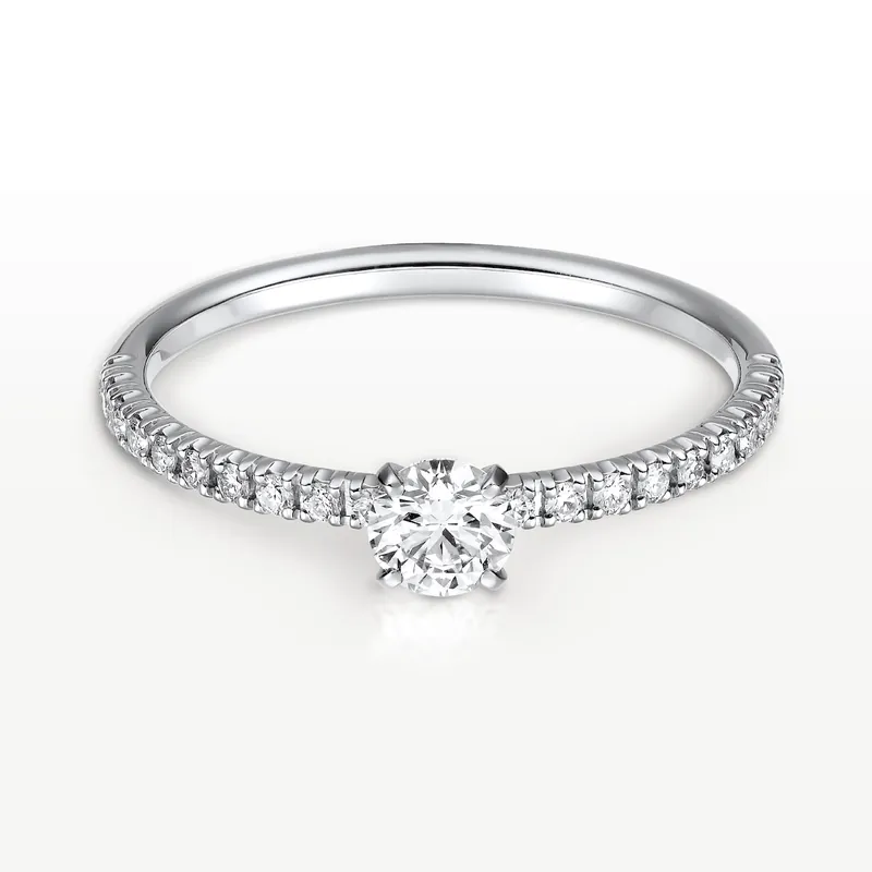 Étincelle de Cartier solitaire in platinum: a brilliant-cut diamond on a thin band paved with small diamonds, on a pale ground.