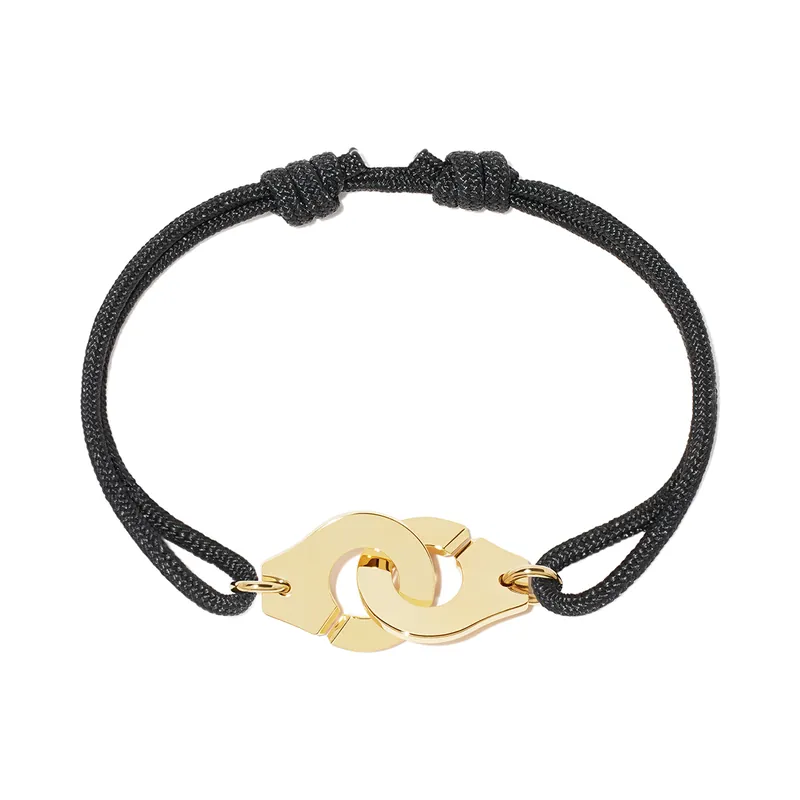 Menottes dinh van bracelet: two interlocking yellow-gold half-rings on a knotted black cord, on a white ground.