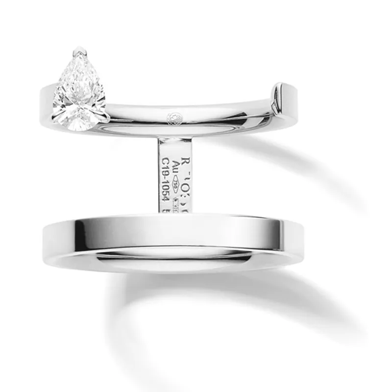 Serti sur Vide ring in white gold: two open bands joined by a short bar, with a pear-cut diamond held above them, on a light grey ground.