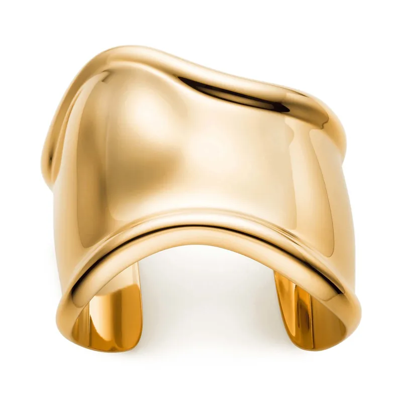 Elsa Peretti medium Bone cuff in 18k gold, for the left wrist, polished and undulating, on a white ground.