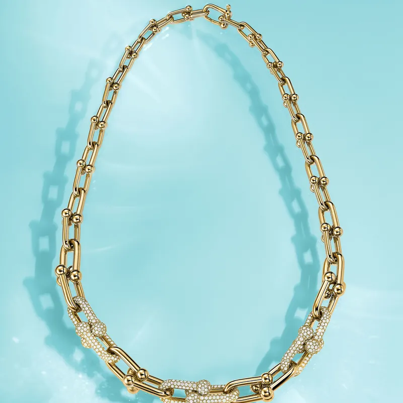 Tiffany HardWear link necklace in 18k yellow gold with a run of pavé diamond links, laid out on a Tiffany Blue ground.