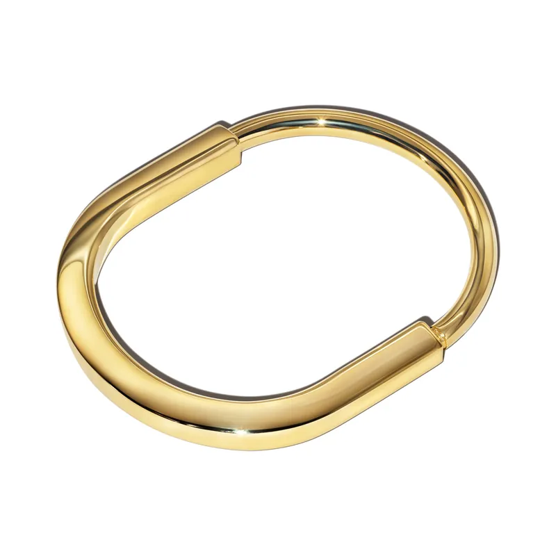 Tiffany Lock bangle in 18k yellow gold, medium, its padlock-shaped clasp at the top, on a white ground.